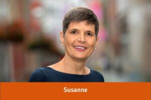Susanne mit kurzen dunklen Haaren und blauem Shirt lächelt in die Kamera