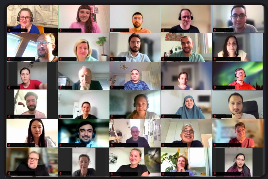 30 Personen in einer Videokonferenz, lächelnd und aufmerksam, beim wöchentlichen Kennenlernen-Gespräch.