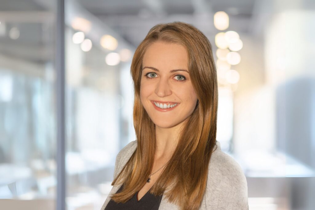 Mona, eine junge Frau mit langen blonden Haaren lächelt in die Kamera