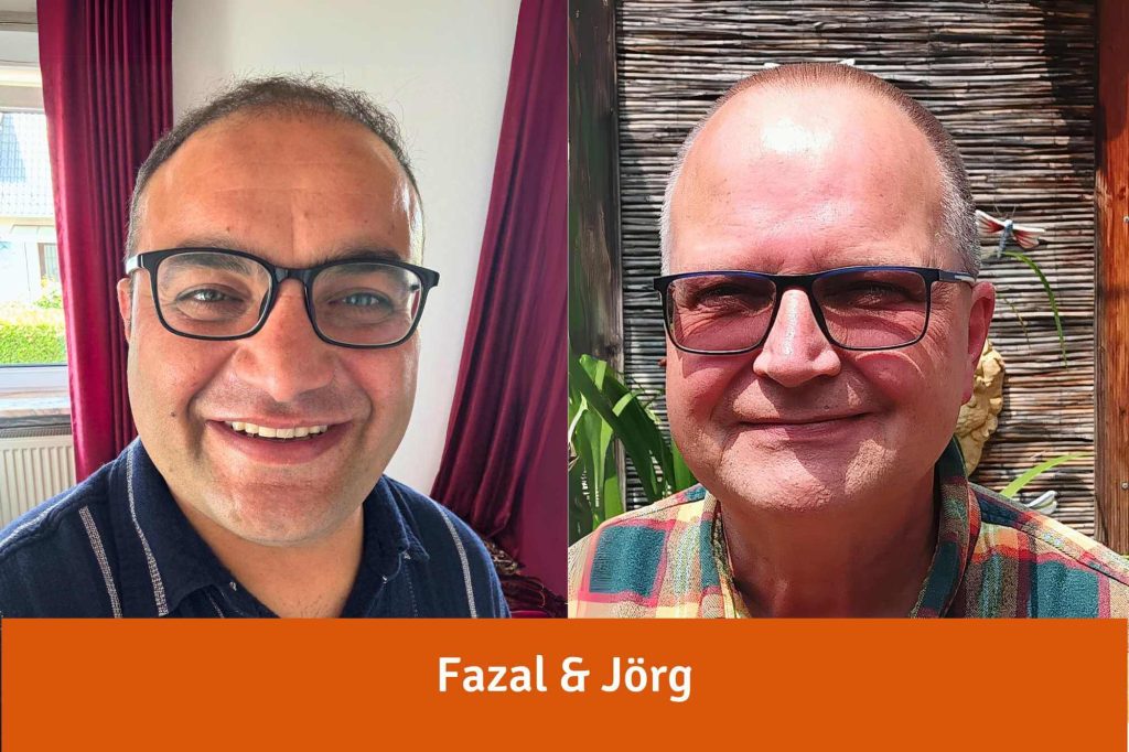 Fazal und Jörg, zwei Männer mit Brille und lichter werdendem Haar lächeln in die Kamera