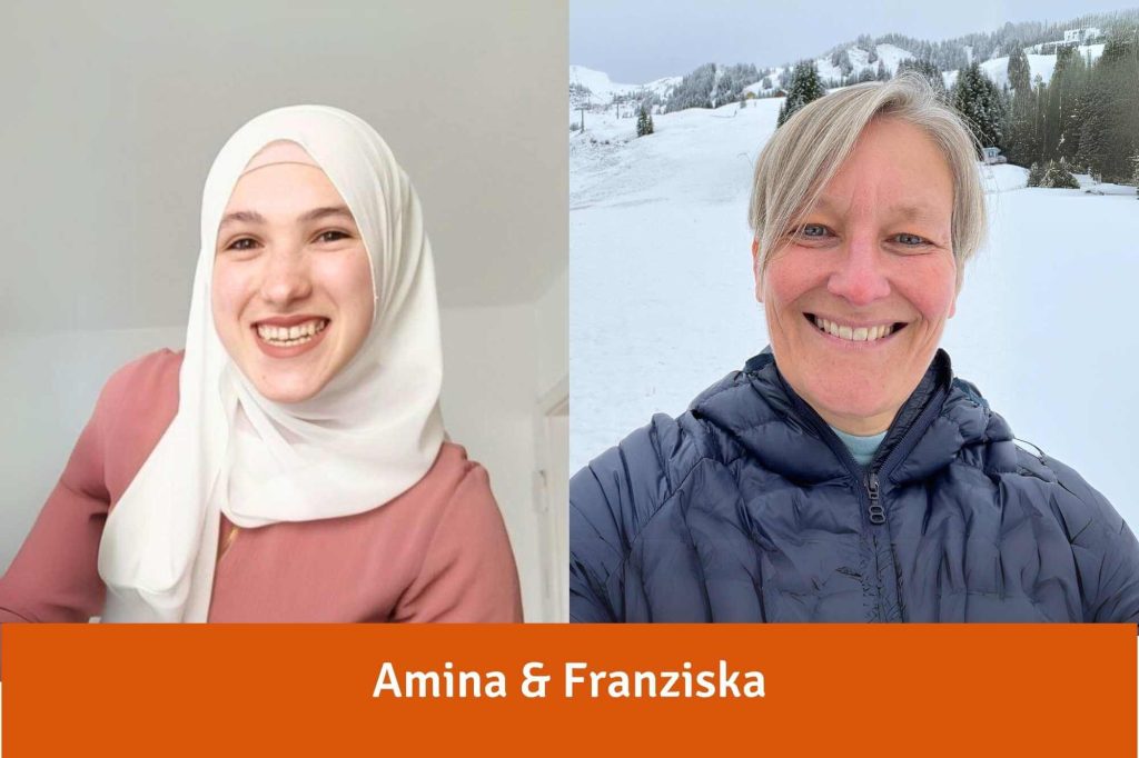 Amina, eine junge Frau mit Kopftuch, und Franziska, eine sportliche Frau mit blondem Kurzhaarschnitt im Schnee lachen in die Kamera