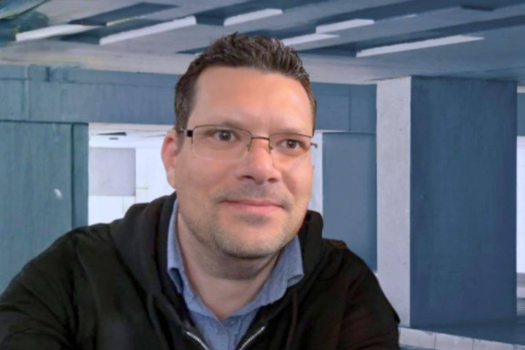 Ein Mann mit Brille und kurzen braunen Haaren lächelt