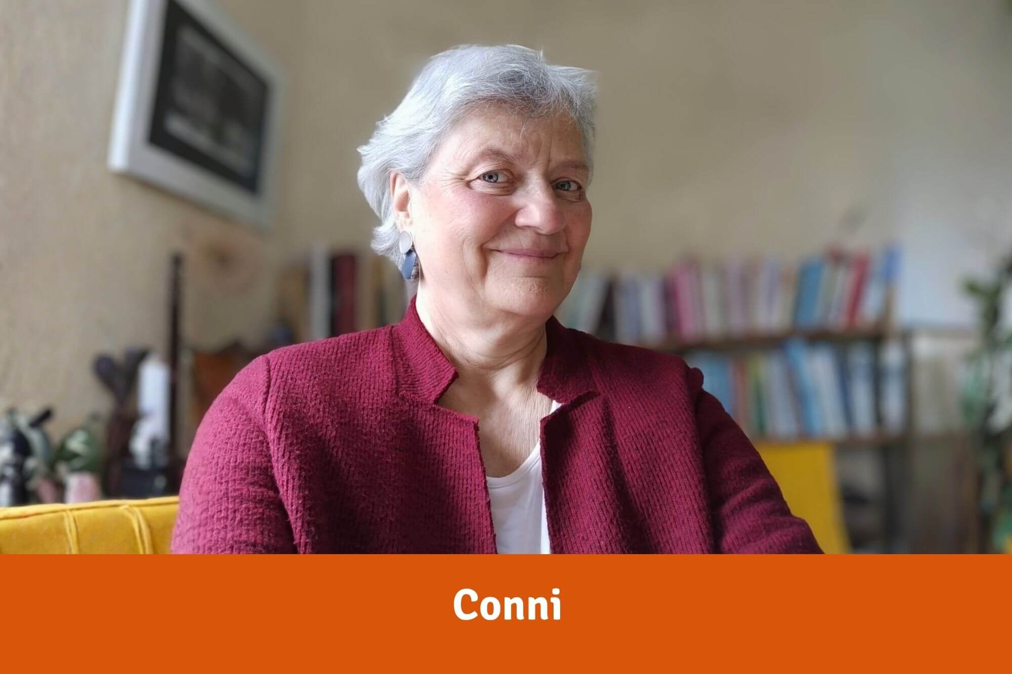Eine ältere Dame mit kurzen grauen Haaren vor einem Bücherregal